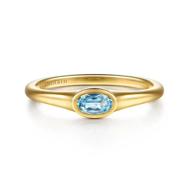 Gold ring with a blue gemstone on a white background