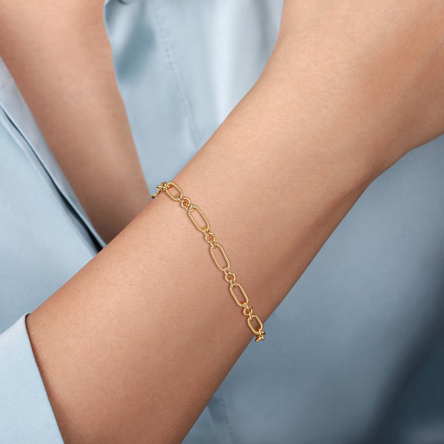 Gold bracelet on a person's wrist against a light blue background