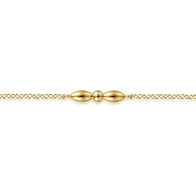 A delicate gold chain bracelet featuring a central decorative clasp with two elongated teardrop beads and a small central bead, shown against a plain white background.