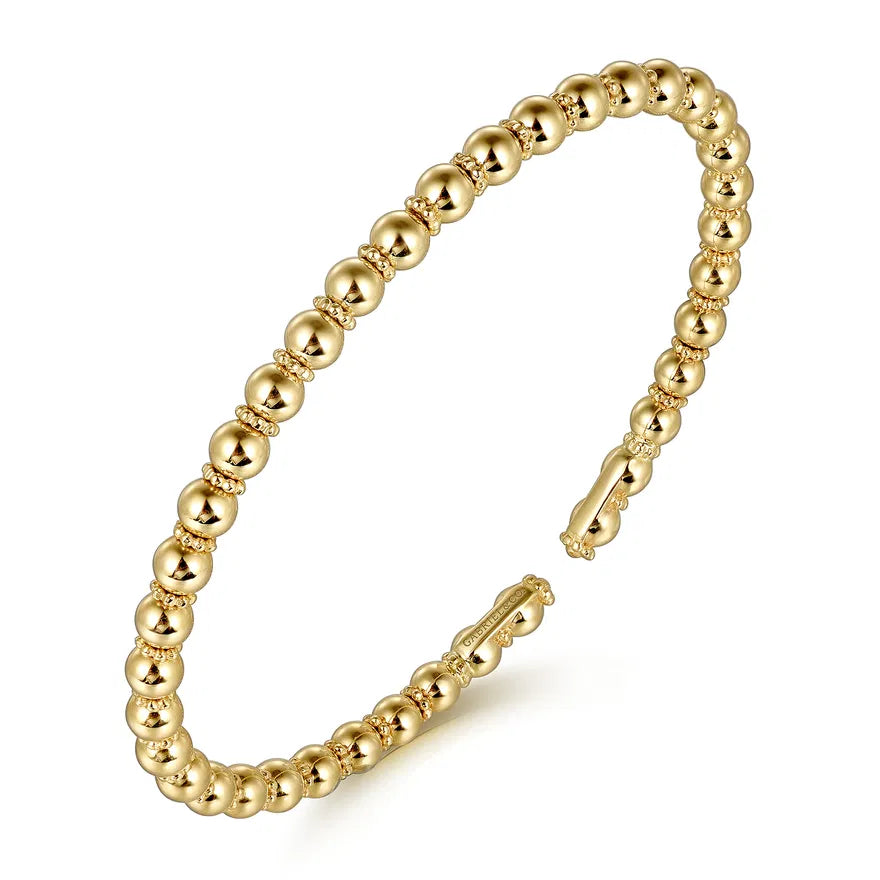 Gold beaded bracelet on a white background angled