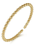 Gold beaded bracelet on a white background angled