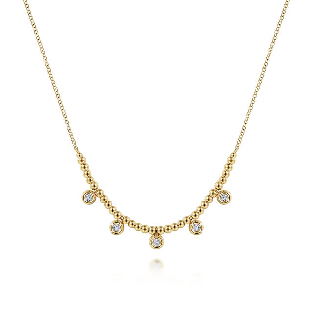 A delicate gold necklace featuring a beaded chain with five small bezel-set round clear gemstones, displayed on a clean white background.