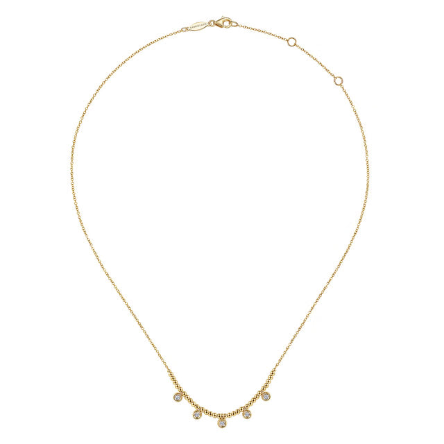 A delicate gold chain necklace with a small curved row of clear  round drop gemstones at the center, displayed on a clean white background.