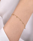 Gold bead station bracelet on a person's wrist with a plain background