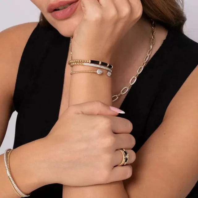 Close-up of a person wearing gold jewelry including a necklace, bracelet, and ring.