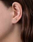 Close-up of an ear wearing a diamond stud earring with brown hair.