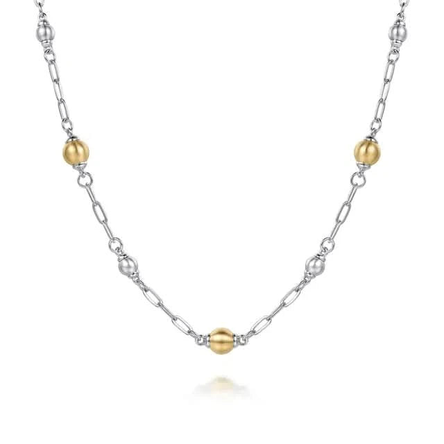 Necklace with alternating gold and silver beads on a white background close up