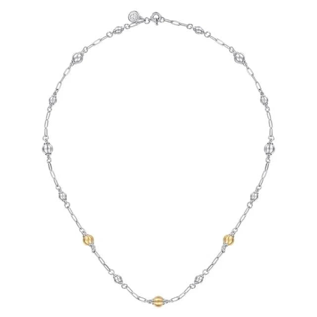 Silver necklace with small gold beads on a white background