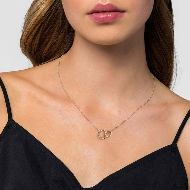 Necklace with interlocking rings worn by a model against a neutral background