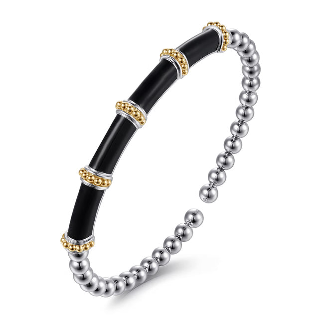 A two-tone stretch bangle bracelet featuring a glossy black central tube section with gold and silver metallic accents, connected to a silver beaded section, shown on a white background. Angled