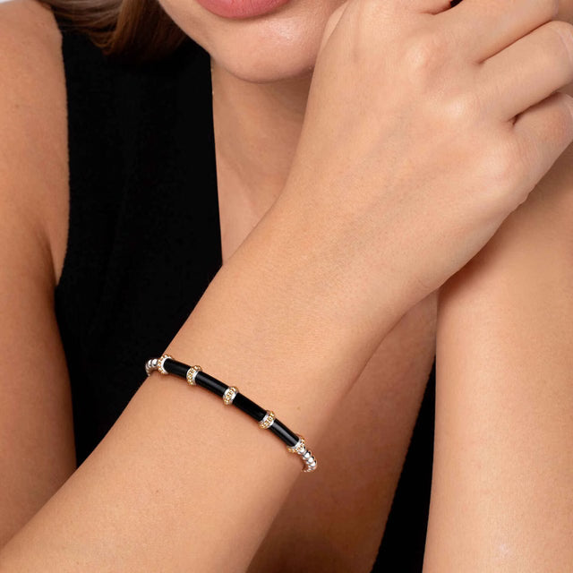 Close-up of a person wearing a black beaded bracelet on a plain background