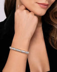 Silver with gold accents bracelet on a wrist with a neutral background