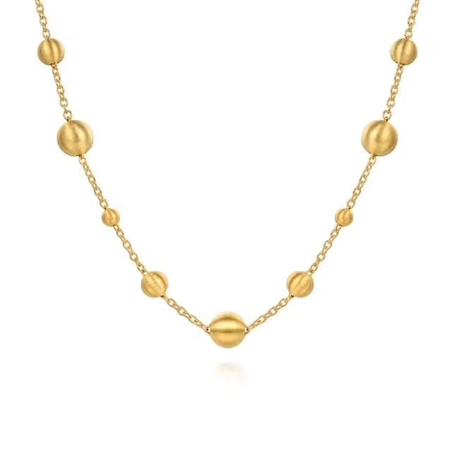 Gold necklace with spherical beads on a white background