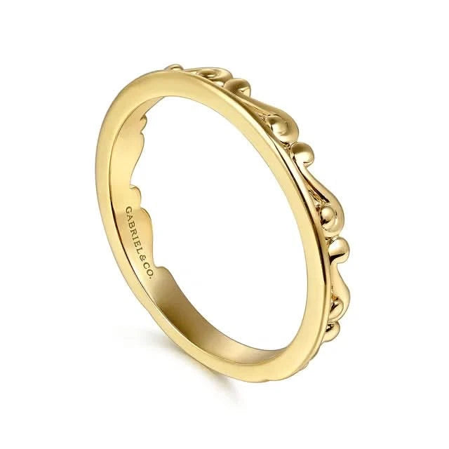 Gold ring with intricate design on a white background angled