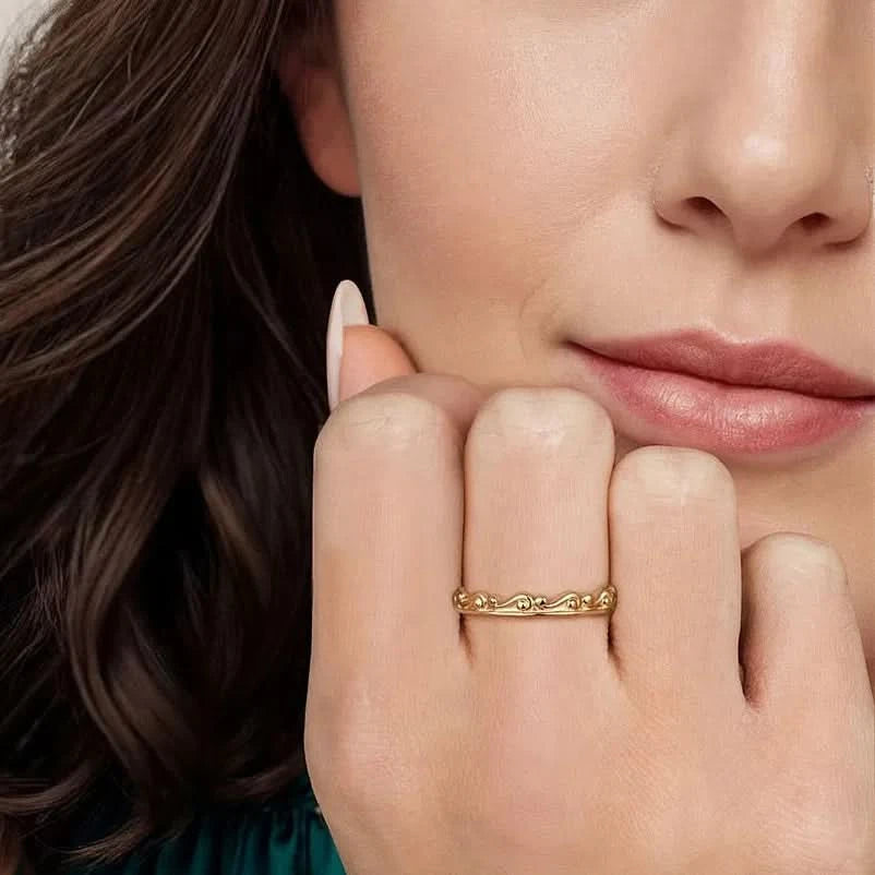Close-up of a woman's hand with a gold ring on her finger, touching her chin.