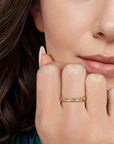 Close-up of a woman's hand with a gold ring on her finger, touching her chin.
