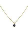 An 18k yellow gold solitaire pendant necklace by Skeie's Jewelers, featuring a 0.55 carat, 5mm round brilliant-cut blue tanzanite gemstone secured in a four-prong basket setting on an 16-inch gold cable chain.