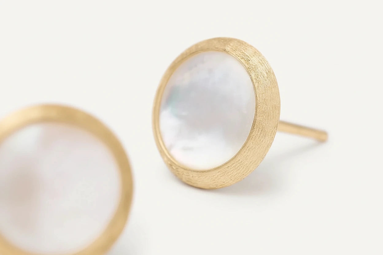 Gold earrings with a white stone on a light background close up