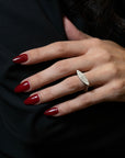 A close-up of a hand with dark red manicured nails wearing a silver marquise-shaped ring set with small clear stones, resting against a black garment background.
