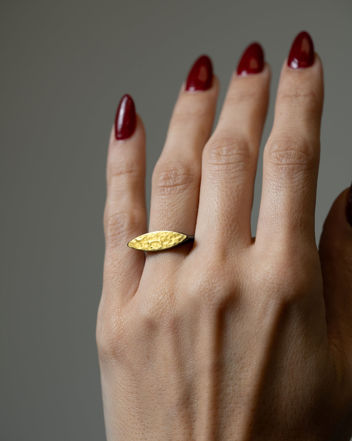 close up of gold marquise shaped ring modeled on a hand