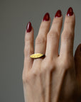 close up of gold marquise shaped ring modeled on a hand