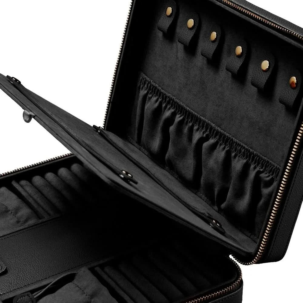 An open black jewelry organizer case with gold-tone zippers and snaps, showing interior compartments, elastic bands, and ring slots on a white background.