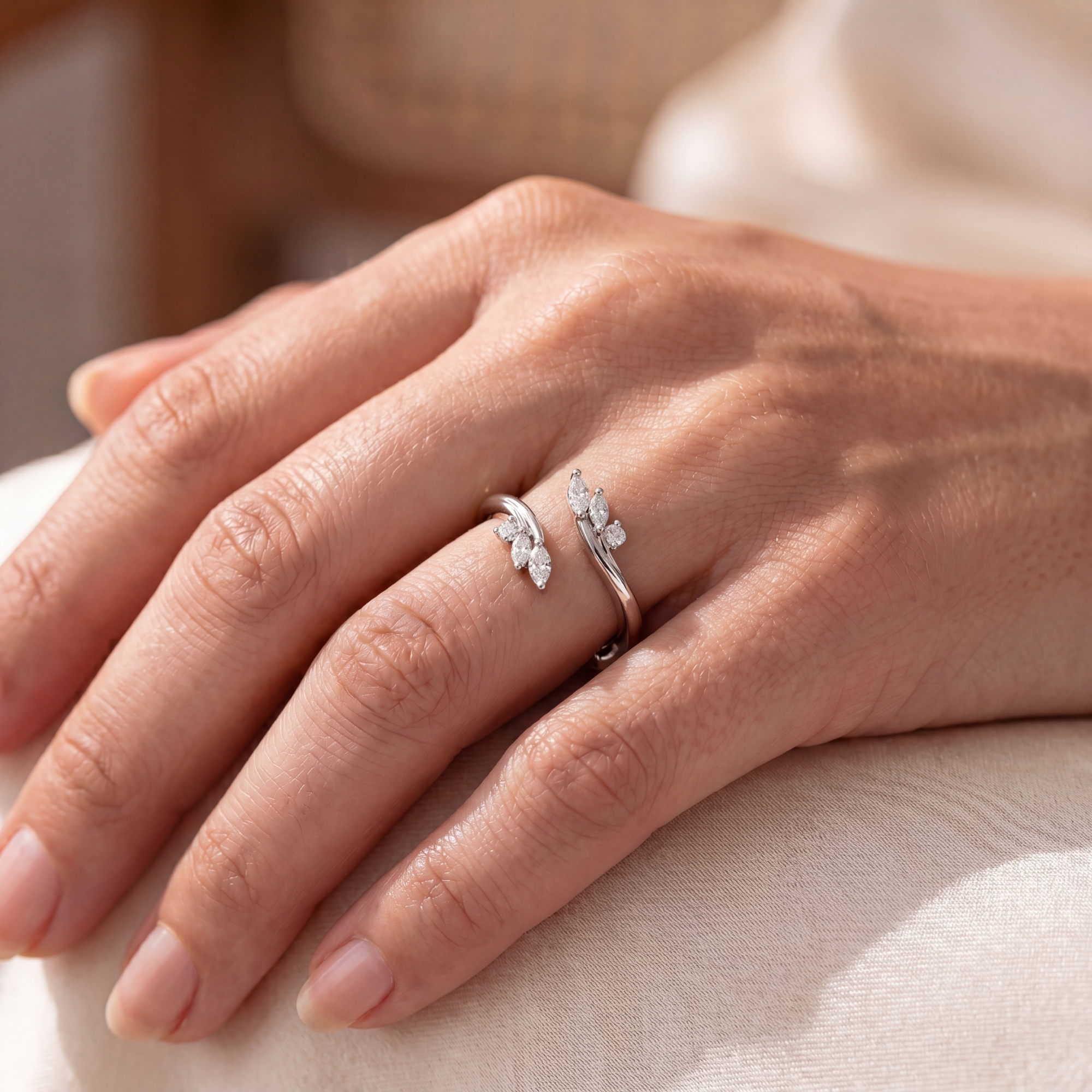 close up of a hand wearing a white open ring with marquise stones