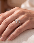 close up of a hand wearing a white open ring with marquise stones