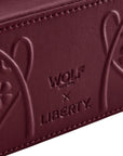 Close-up of a maroon leather product with 'Wolf & X' and 'Liberty' branding.