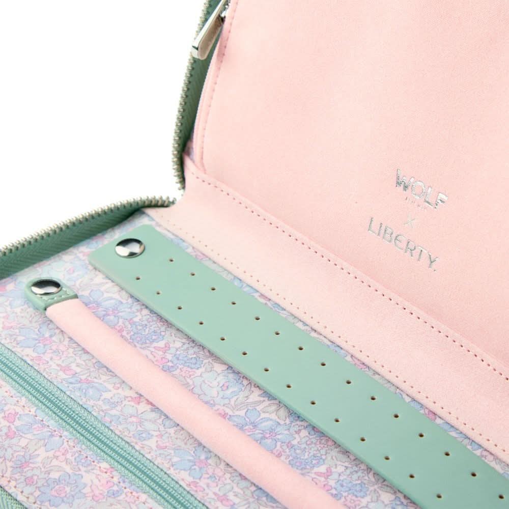 Close-up of a pink and green jewelry organizer with floral patterned section.