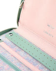 Close-up of a pink and green jewelry organizer with floral patterned section.