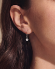 Close-up of an ear wearing a silver earring with a blurred background