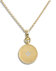 A gold round pendant necklace with a textured rope edge and a small diamond flower motif in the center, suspended from a gold chain on a white background.