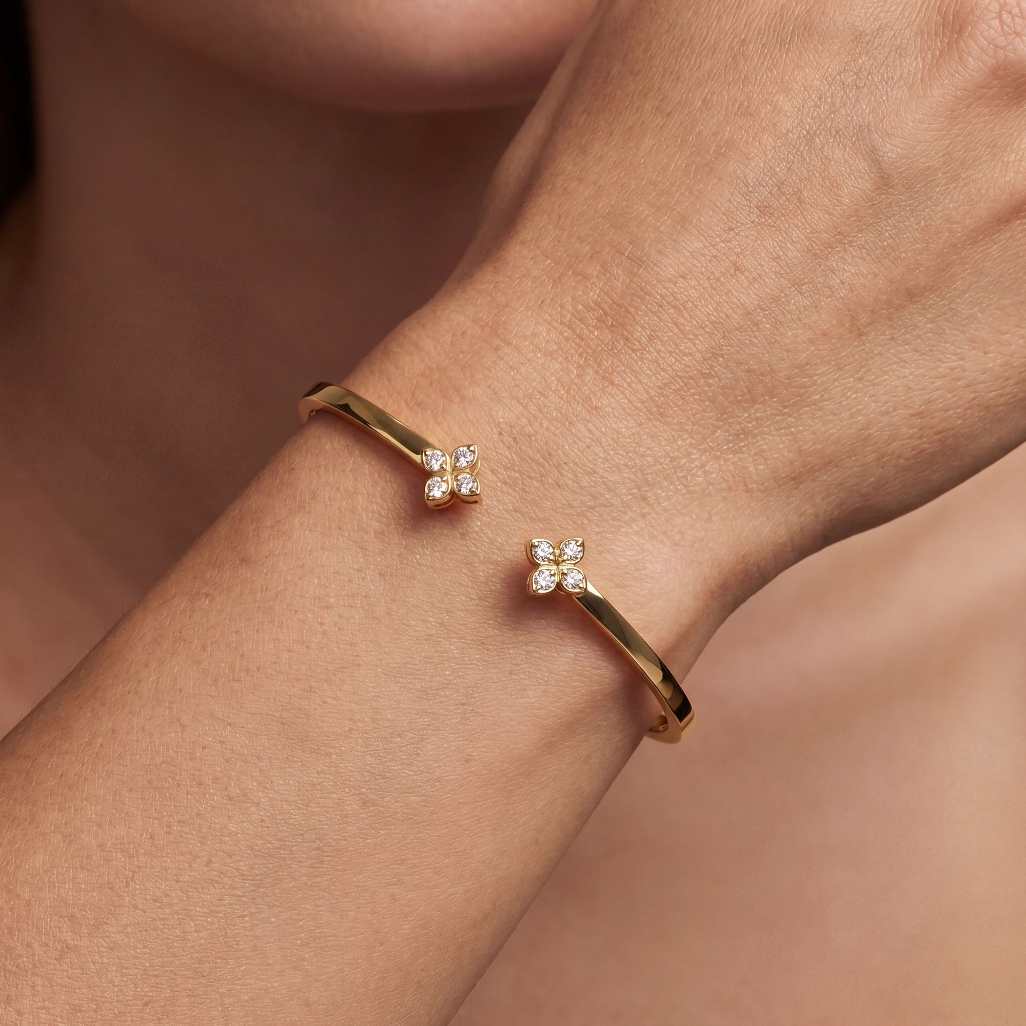 gold bracelet with flowers on wrist close up