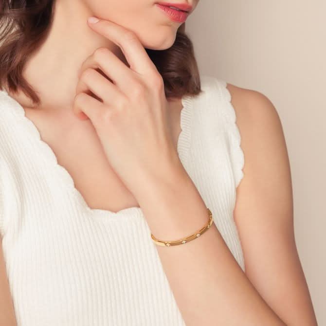 Woman wearing a gold bracelet on a neutral background Roberto Coin Love in Verona Diamond Station Bangle