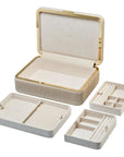 Beige jewelry box with gold accents opened with 3 compartments removed on a white background