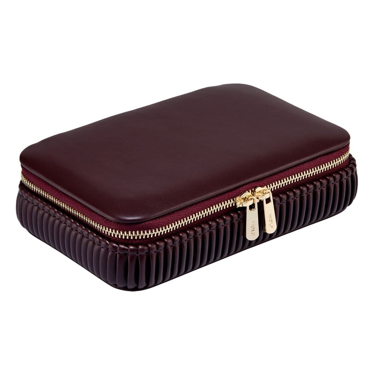 maroon leather jewelry box with gold zipper angled on a white background