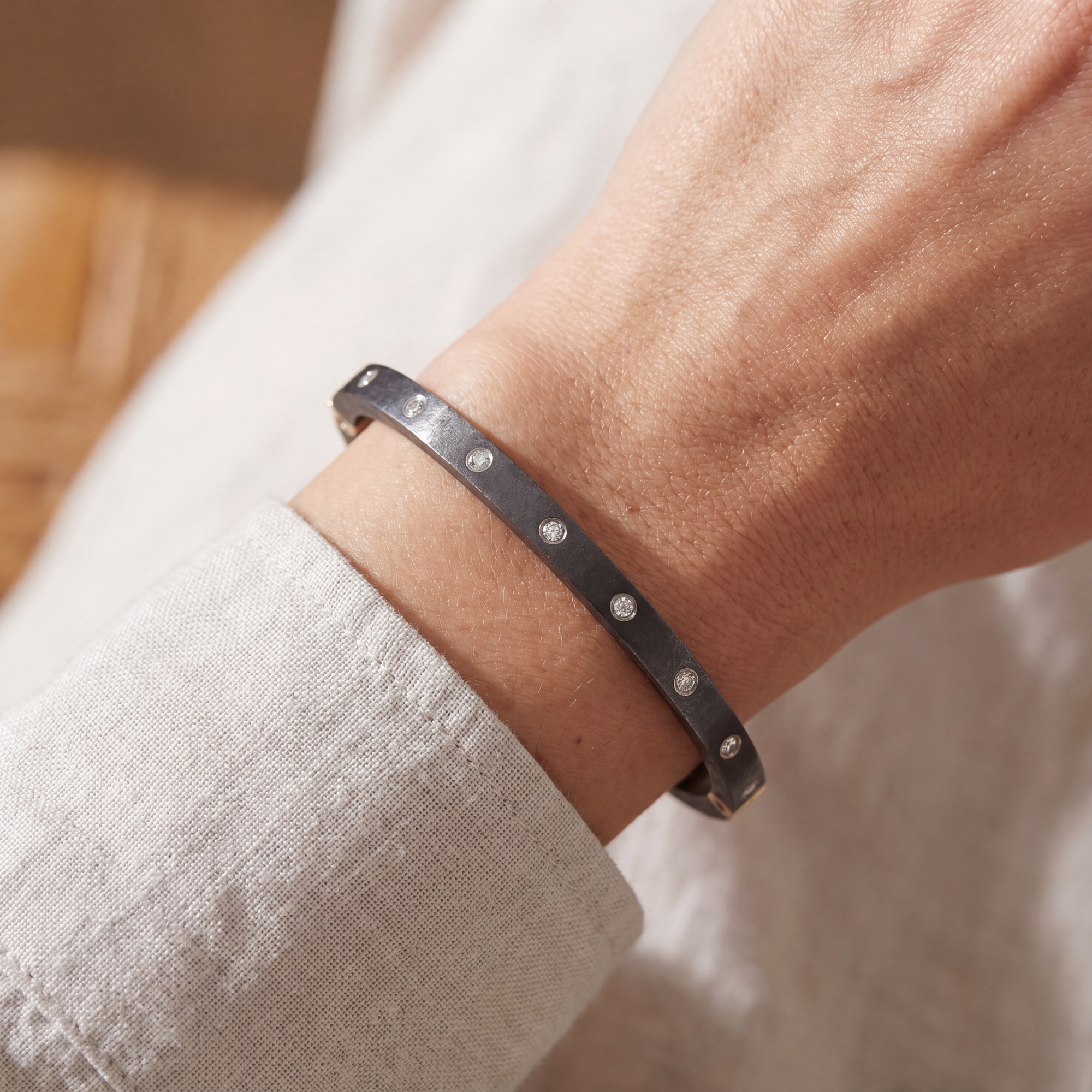 close up of an arm with a black bracelet with embedded diamonds 