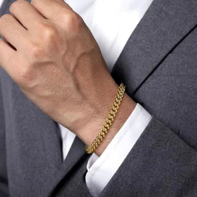Gold bracelet on a person wearing a gray suit and white shirt