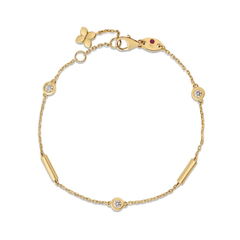 Gold bracelet with flower charm and ruby stone on a white background