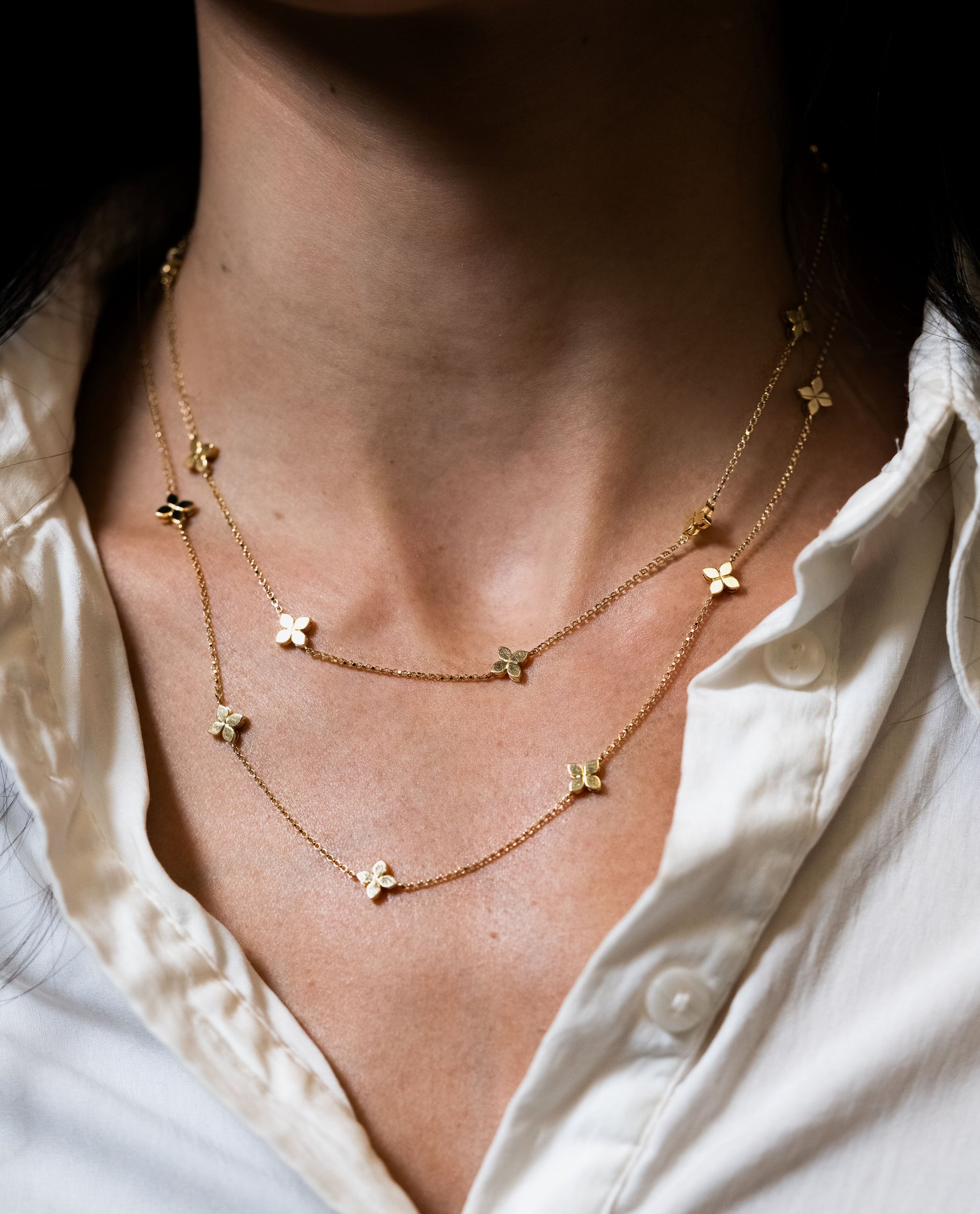 layered gold necklace on neck with white collar shirt