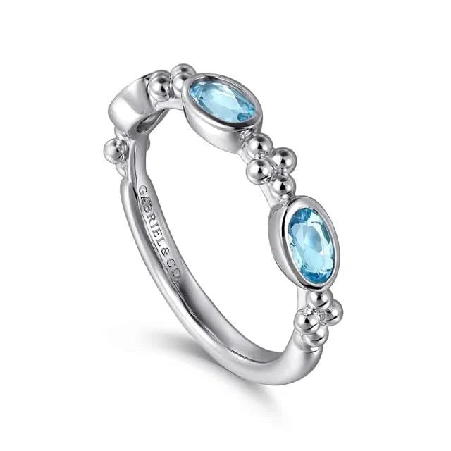 Silver ring with blue gemstones on a white background angled