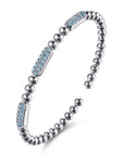 A silver-toned beaded cuff bracelet with three rectangular inlays set with light blue topaz shown angled on a clean white background.