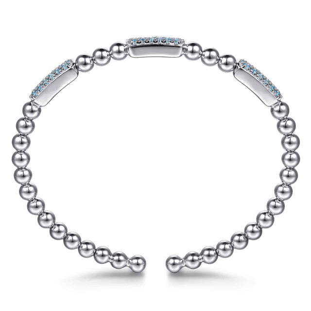 A silver-toned open cuff bracelet featuring a row of small round beads and polished rectangular links, with two links accented by light blue stones, shown on a white background.
