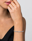 Woman wearing a silver bracelet with blue topaz stones on a neutral background