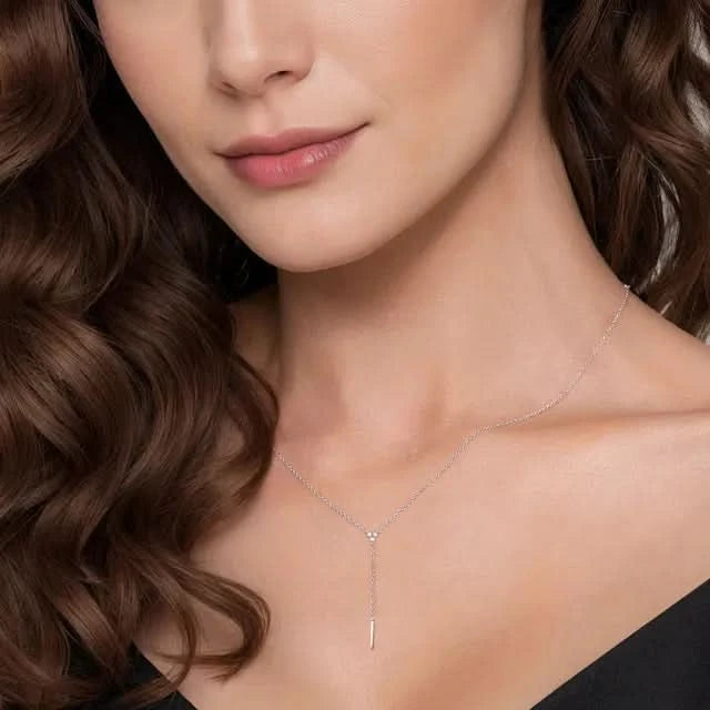 Close-up of a woman wearing a delicate silver necklace with a black background