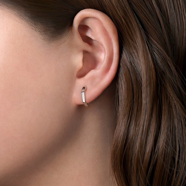 silver hoop earring worn by a person with brown hair.