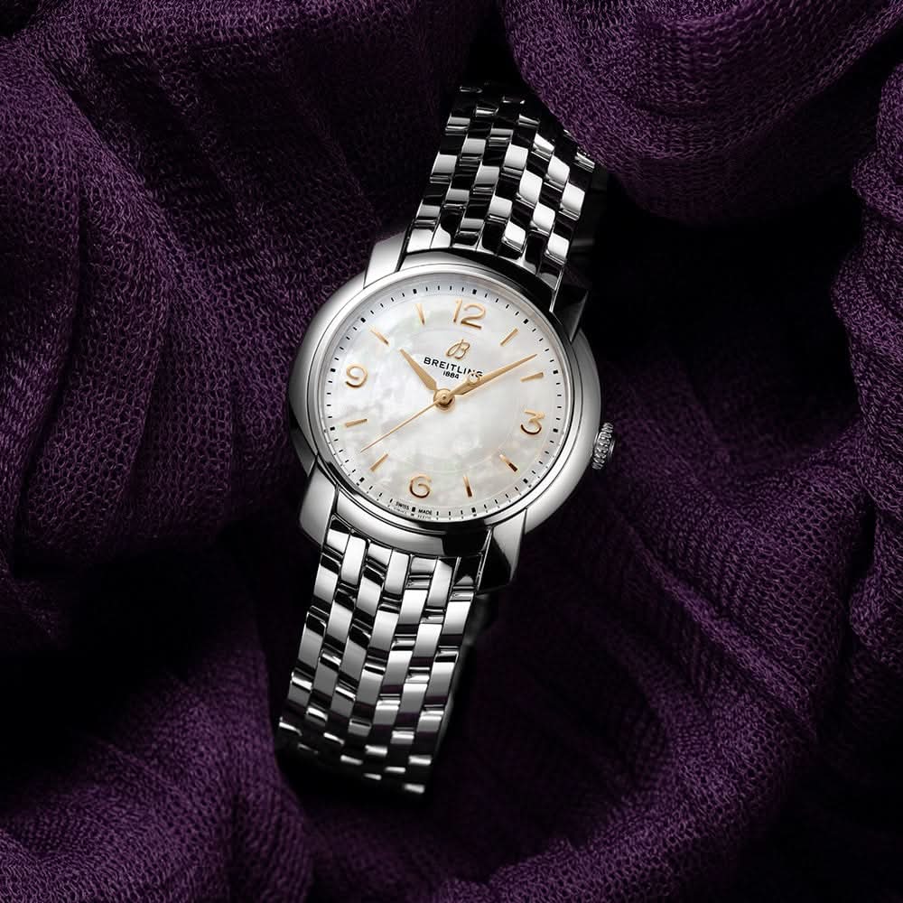 Silver Breitling watch on a textured purple fabric background