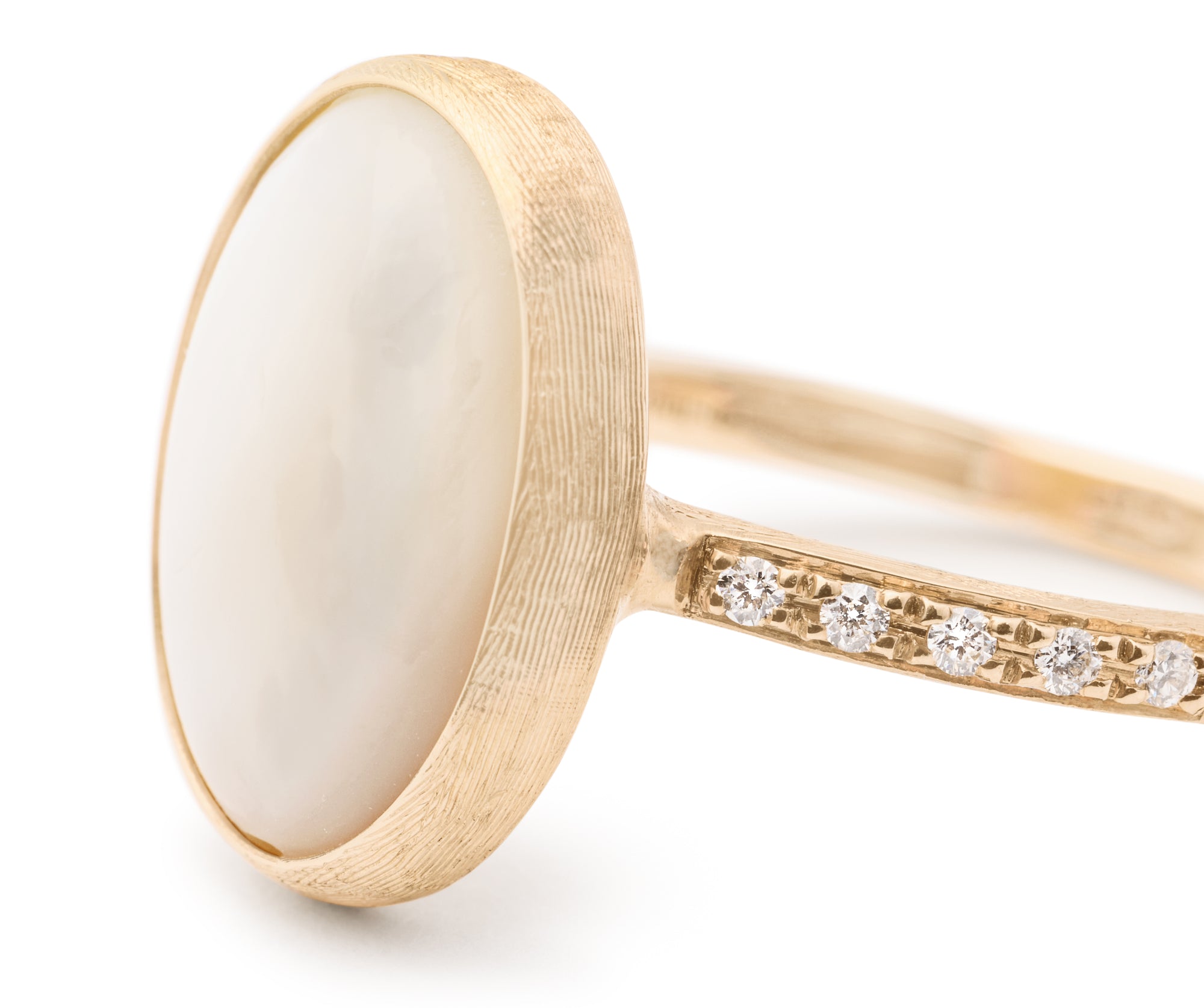 Gold ring with a white mother of pearl stone and diamond-studded band on a white background