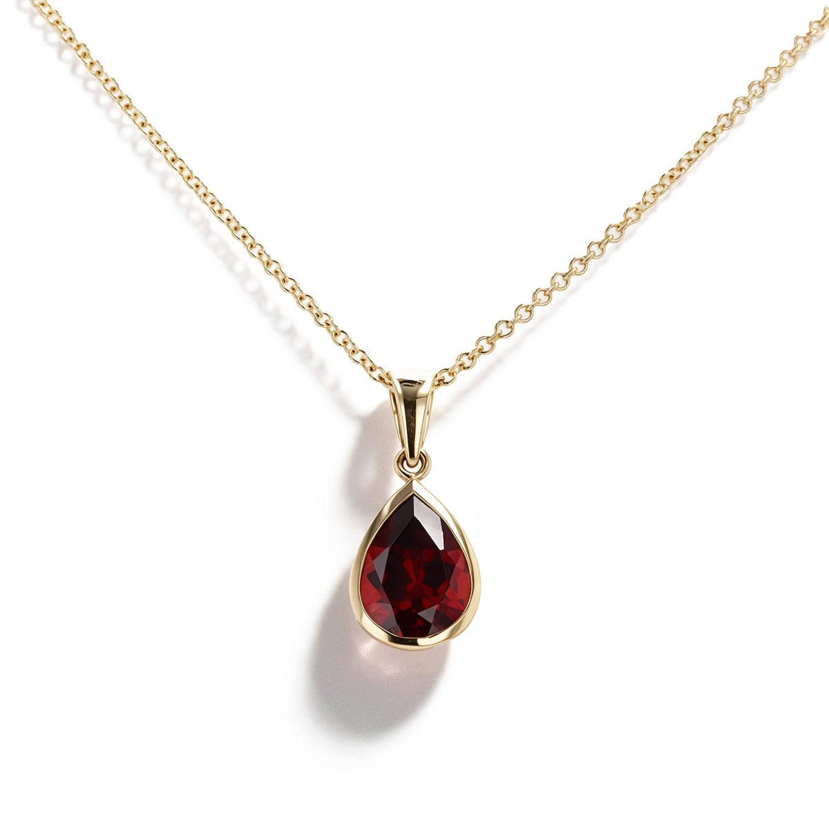 A gold necklace with a teardrop-shaped dark red gemstone pendant, shown on a clean white background with a soft shadow.